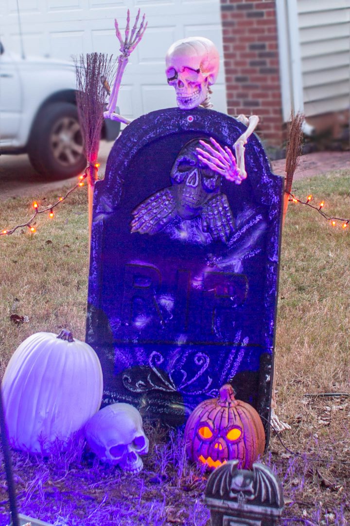 Halloween tombstone staked securely with a skeleton attached to the back of it