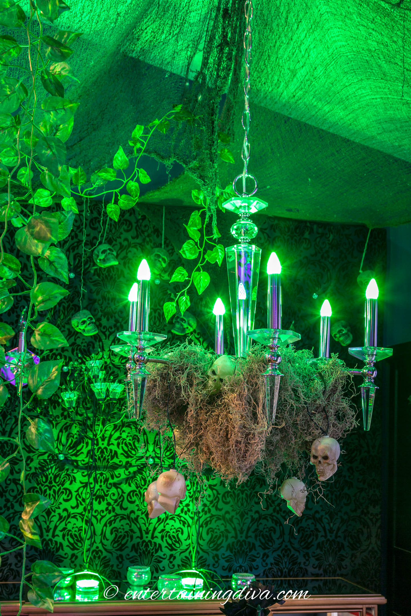 Maleficent party forest decor with green lights and Spanish moss draped on a chandelier