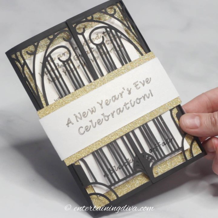 The finished DIY laser cut Gatsby party invitation with a white and gold wrapper