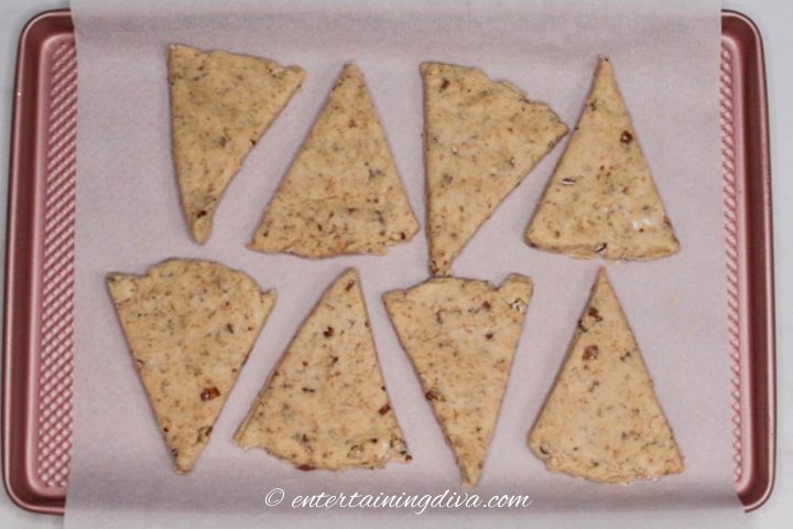 Maple pecan scones wedges on a cookie sheet with parchment paper