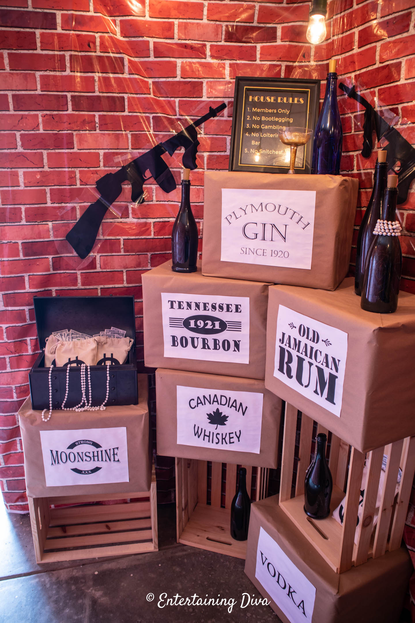 Speakeasy party photo op with cases of liquor, guns and empty wine bottles