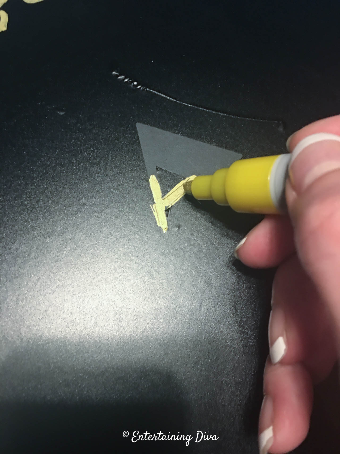 Coloring in the vinyl stencil letters with gold chalk marker