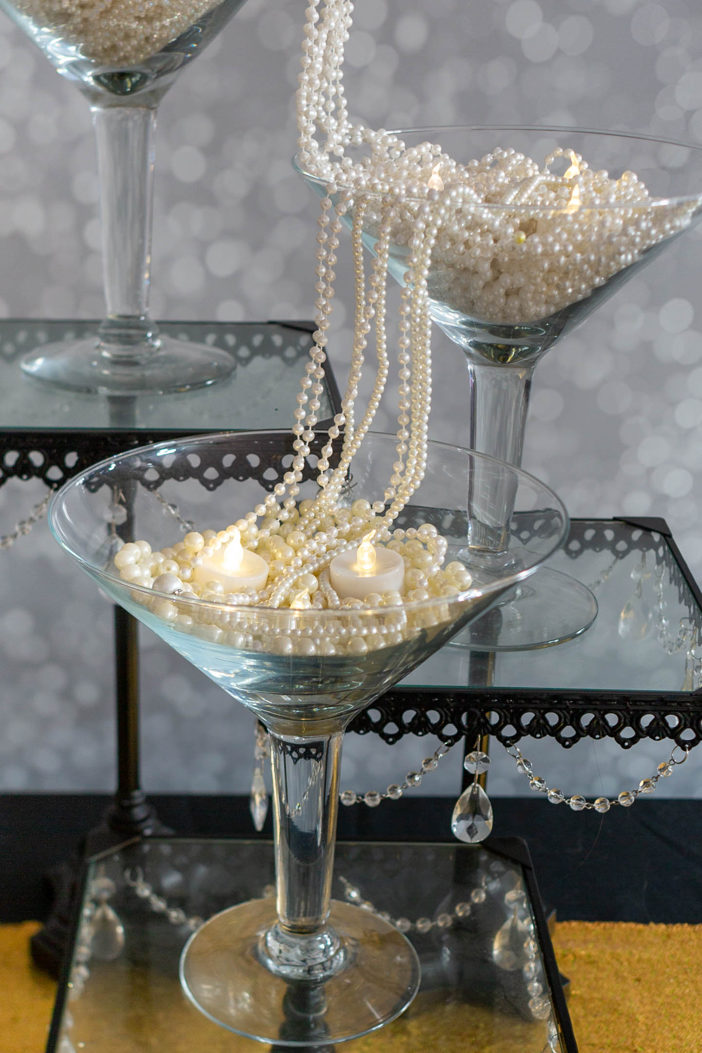 Centerpiece with strings of faux pearls streaming from one large martini glass to another
