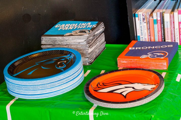 Carolina Panthers and Denver Broncos team plates and napkins on a buffet table covered with a football field tablecloth