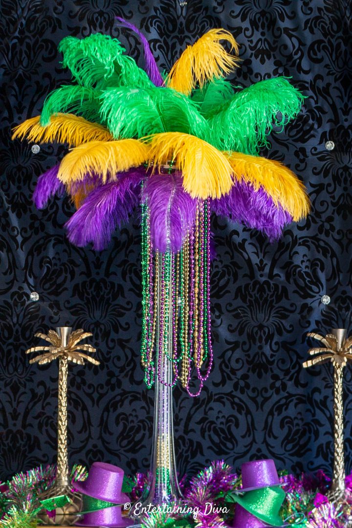Purple, gold and green Mardi Gras feather centerpiece with Mardi Gras beads hanging from the feathers