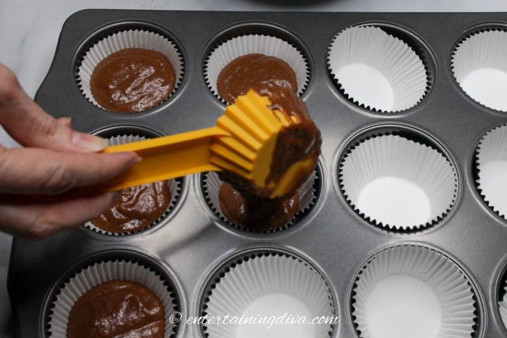 Cupcake liners being filled with chocolate cupcake batter