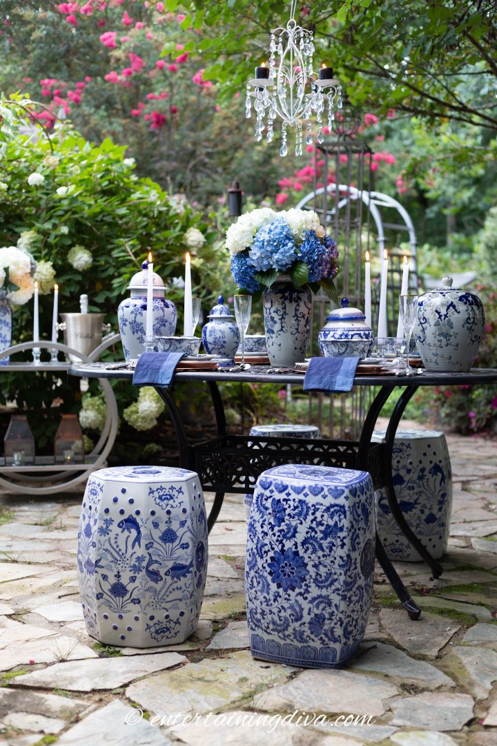 Blue and white outdoor tablescape with garden stools used as chairs
