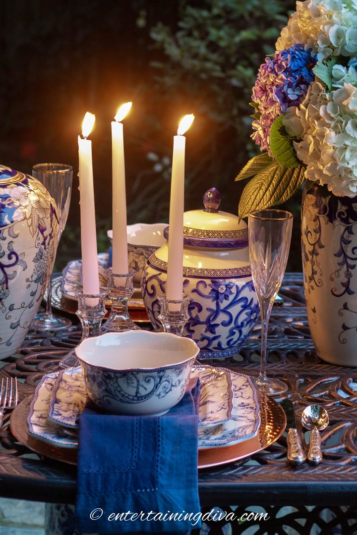 Blue and white ginger jars and candles used as a centerpiece on an outdoor table