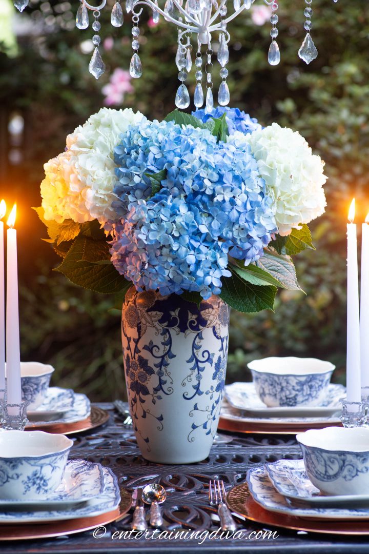 Blue and white ginger jar centerpiece with blue and white hydrangeas on an outdoor table