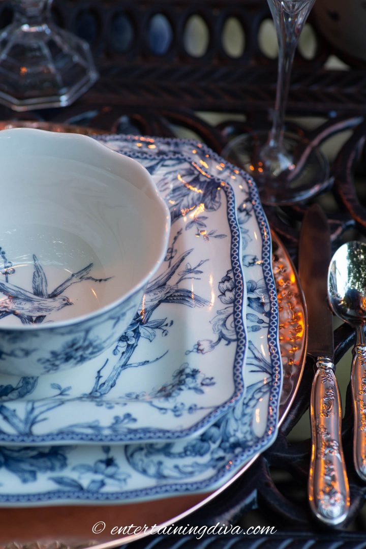 Blue and white dishes with a copper charger on an outdoor table