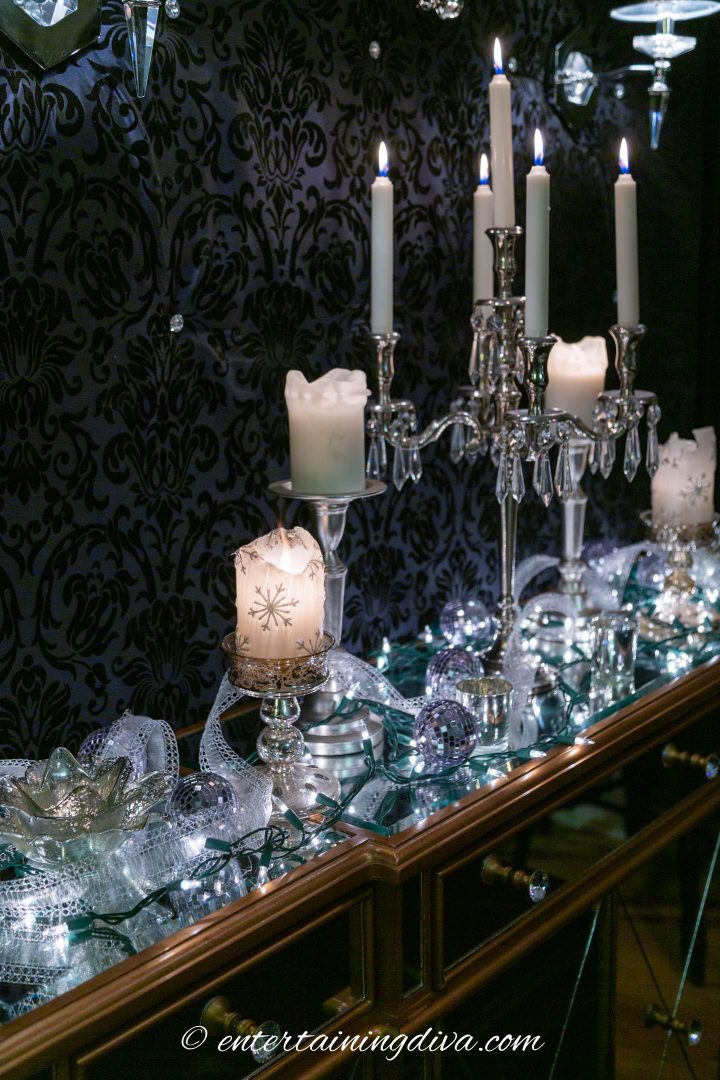 White Christmas lights, candles and silver ribbon on a buffet