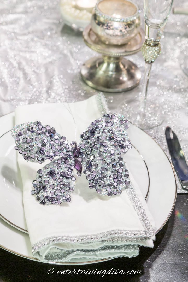 Close up of a silver butterfly Christmas ornament used as a napkin holder on a place setting