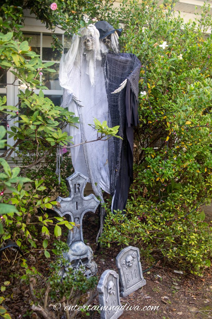 Bride and groom ghosts hidden in the bushes of a Halloween graveyard