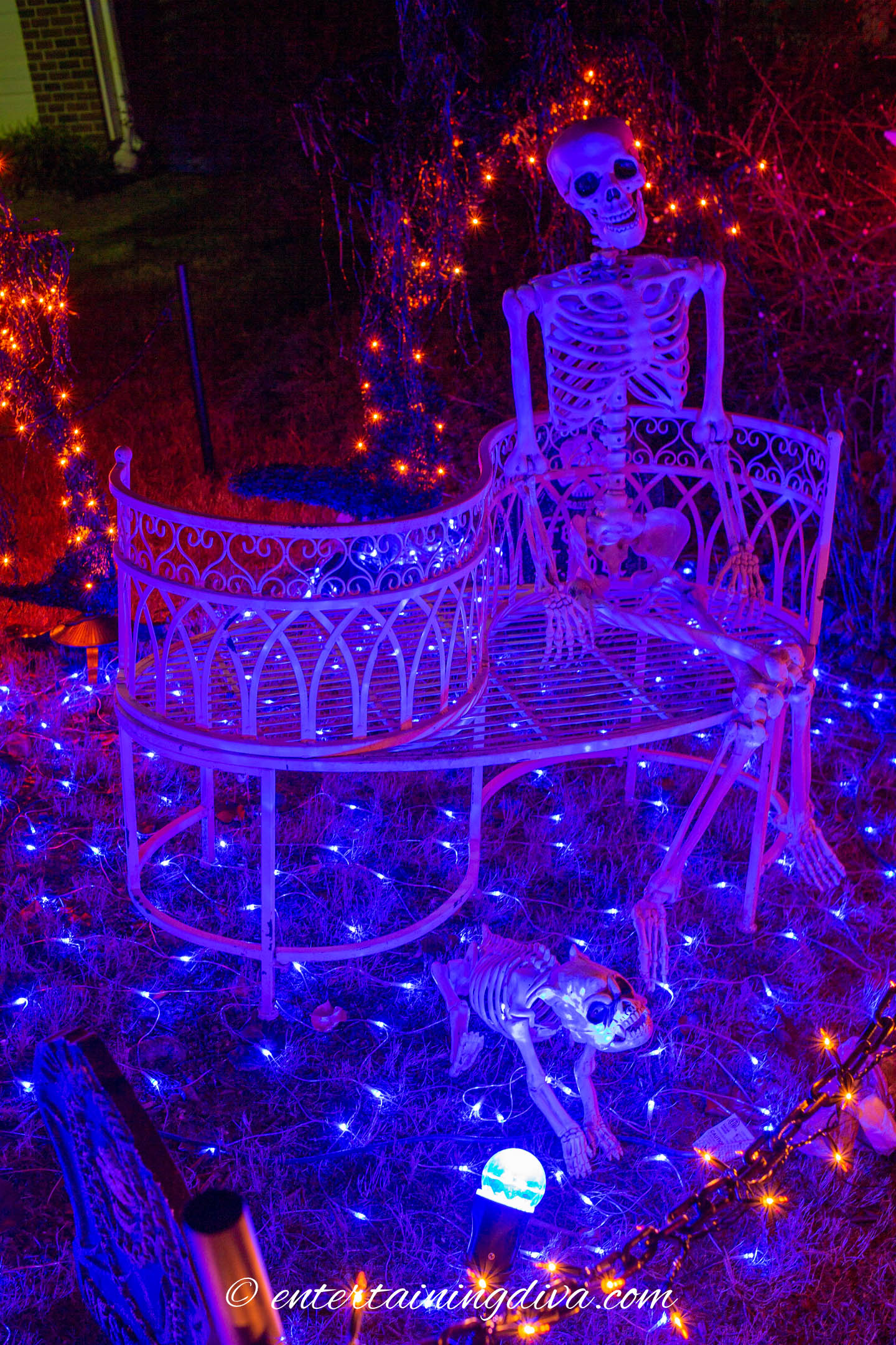 Skeleton on an outdoor bench lit with blue lights.