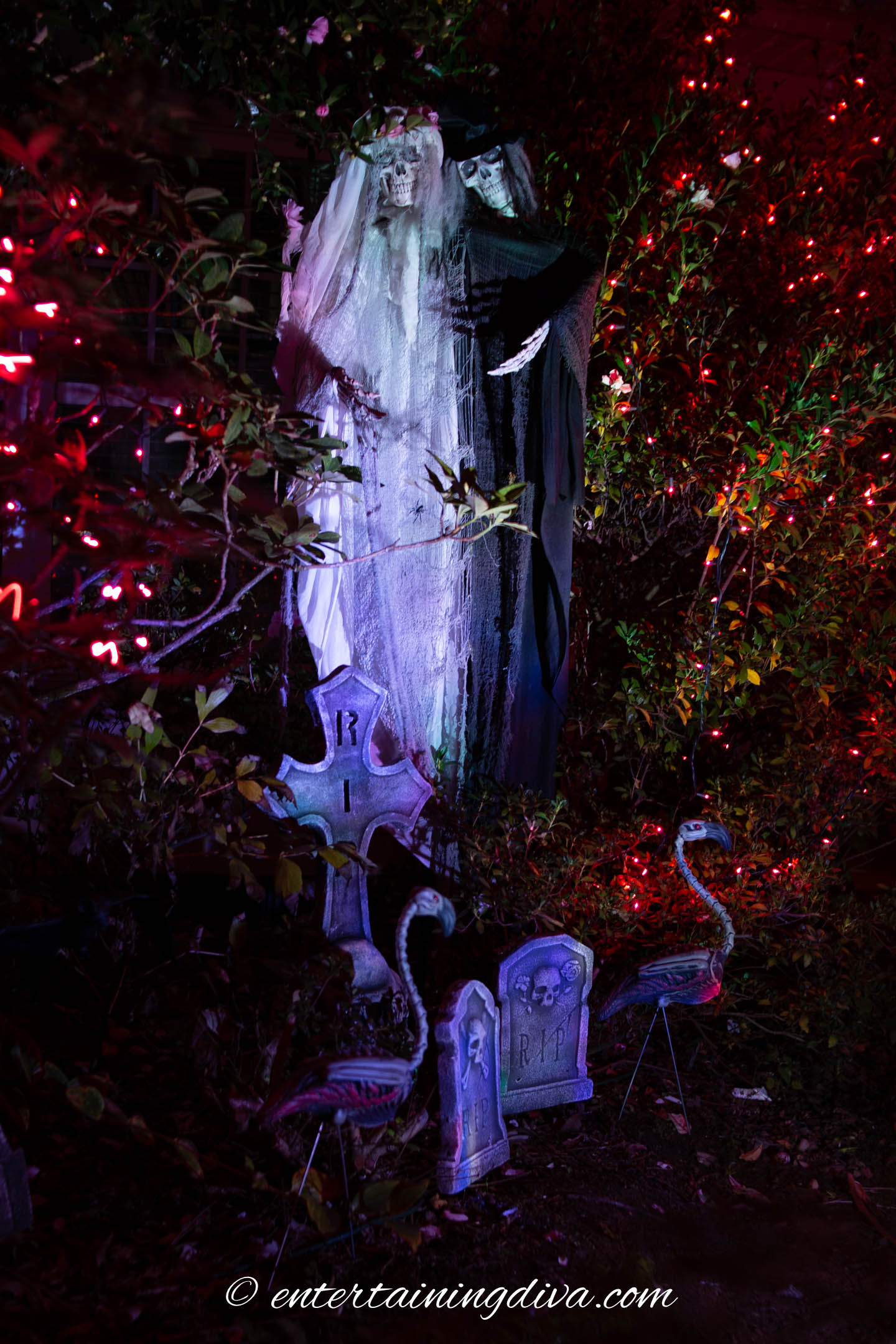 Ghosts, skeleton flamingoes and tombstones lit up at night with Halloween outdoor lighting