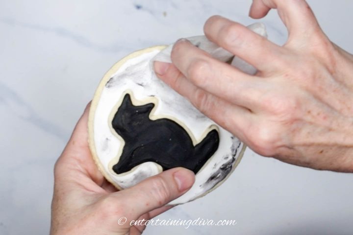 Wet paper towel wiping off excess black icing.