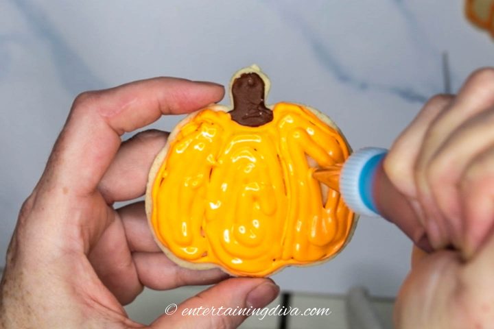 Pumpkin cookie flooded with orange royal icing