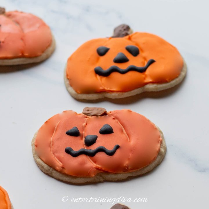 Halloween pumpkin cookies decorated with black royal icing faces