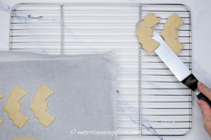 bat cookies being moved to a wire cooling rack
