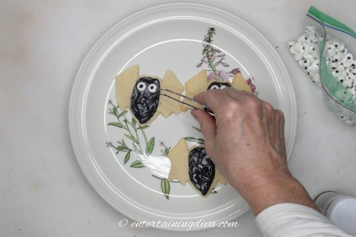 Candy eyes being added to the Halloween bat sugar cookie
