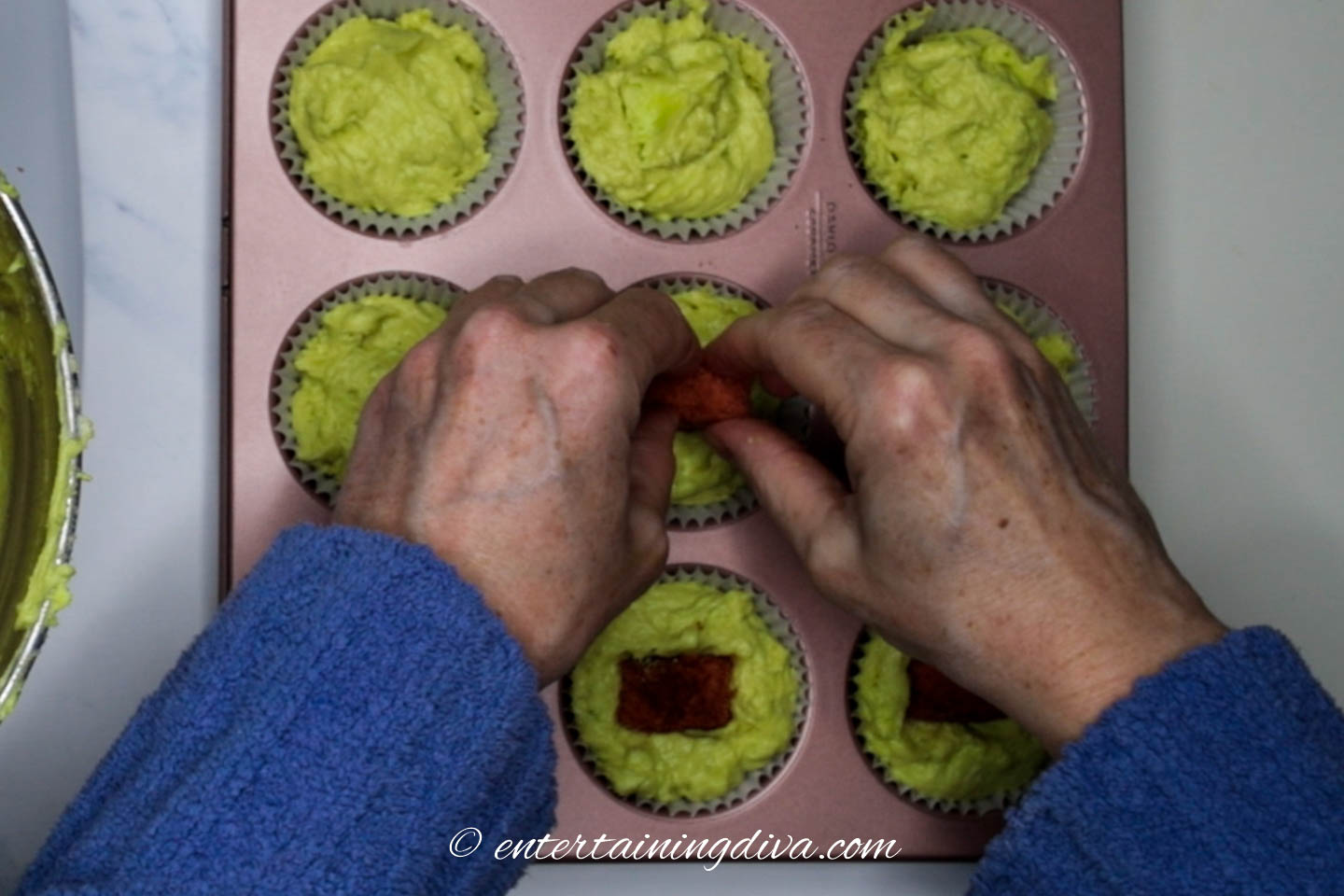 Hearts being pushed into the green cupcake batter