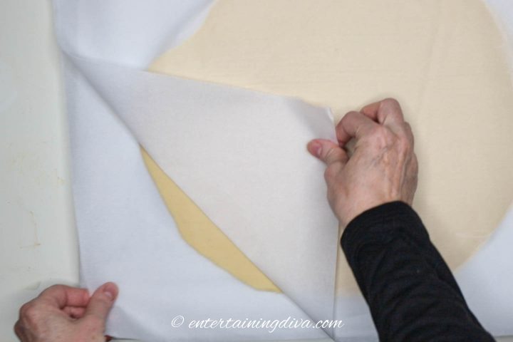Parchment paper being peeled off the chilled cookie dough