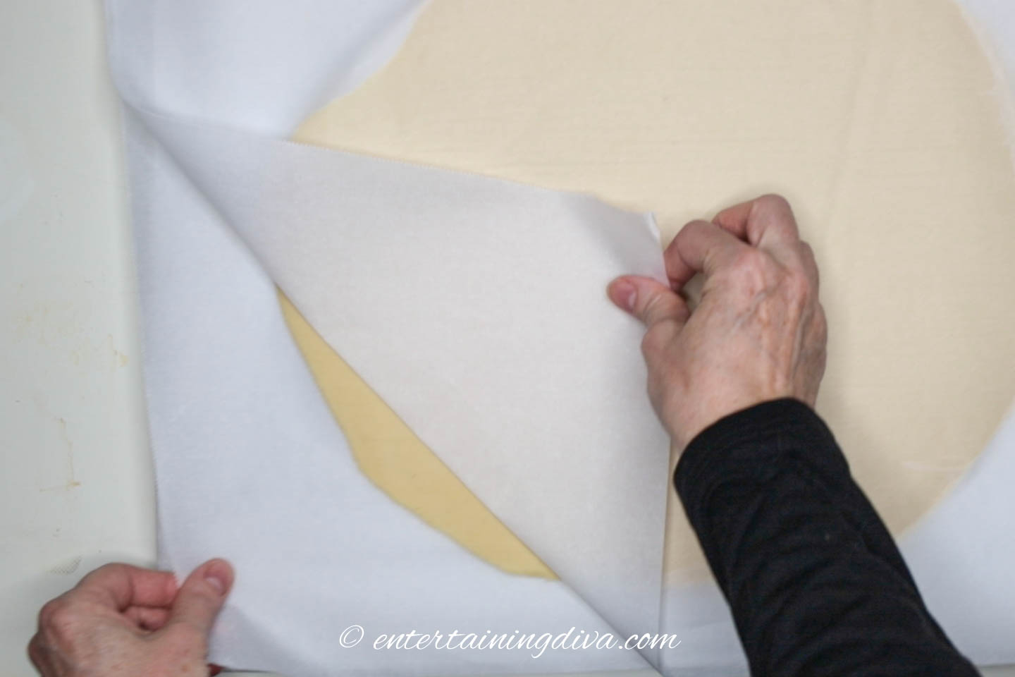Parchment paper being peeled off the chilled cookie dough