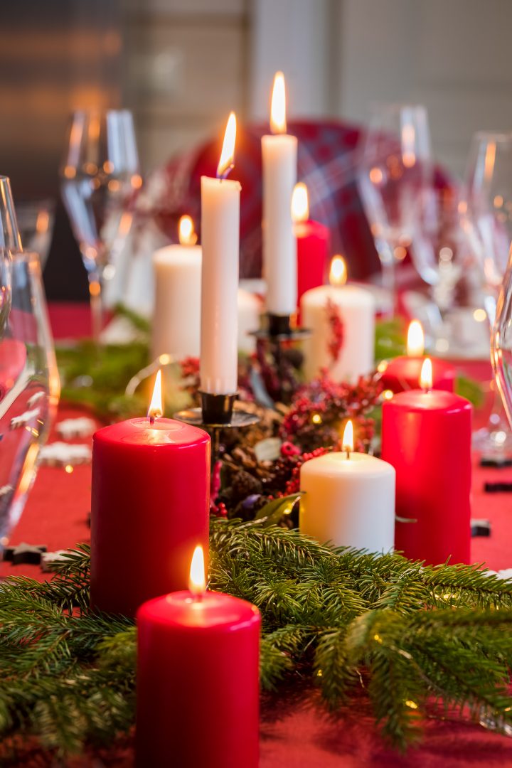 DIY Christmas centerpiece made from red and white candles with evergreens and red berries