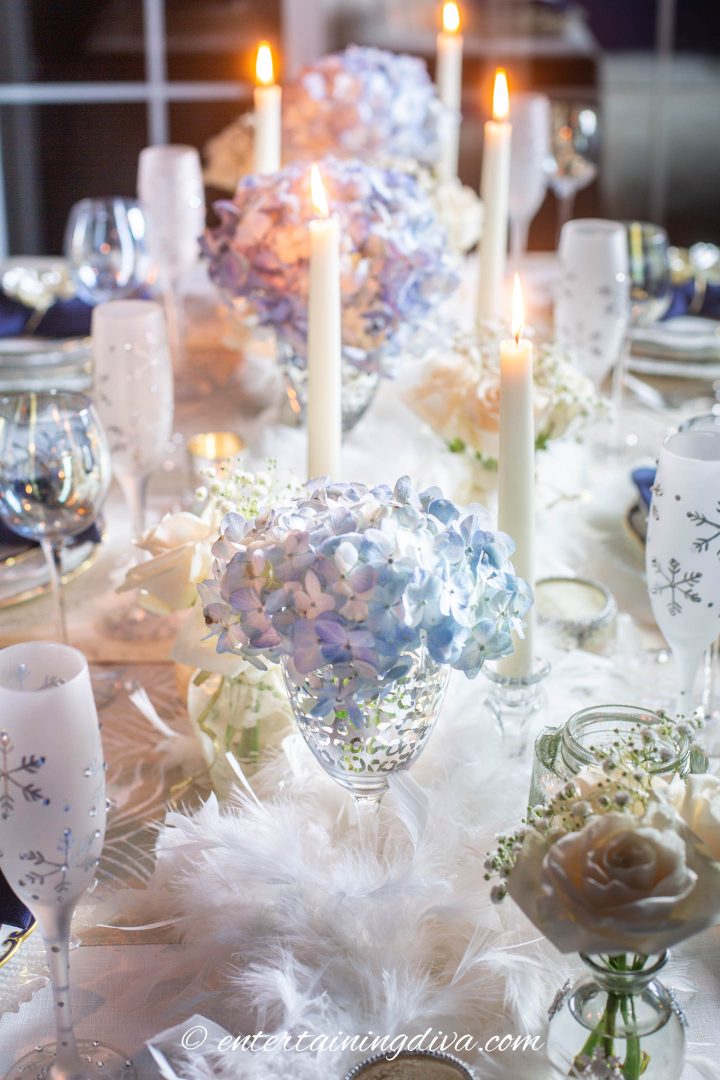 Wintry centerpiece made with white feather boas, blue and white flowers and white candles