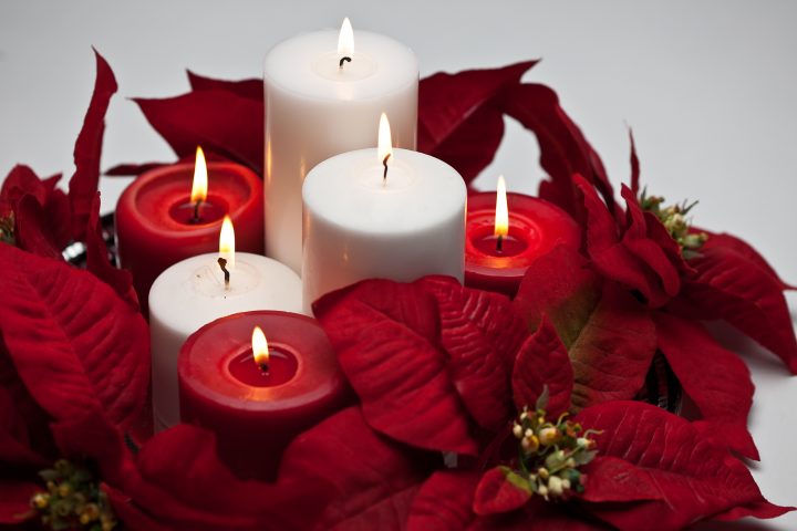 Small DIY Christmas centerpiece made with poinsettias, and red and white pillar candles