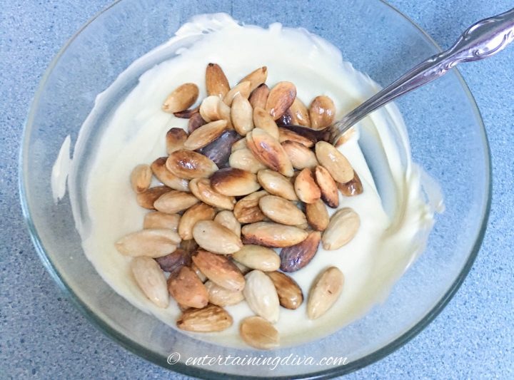 Roasted almonds and melted white chocolate in a bowl