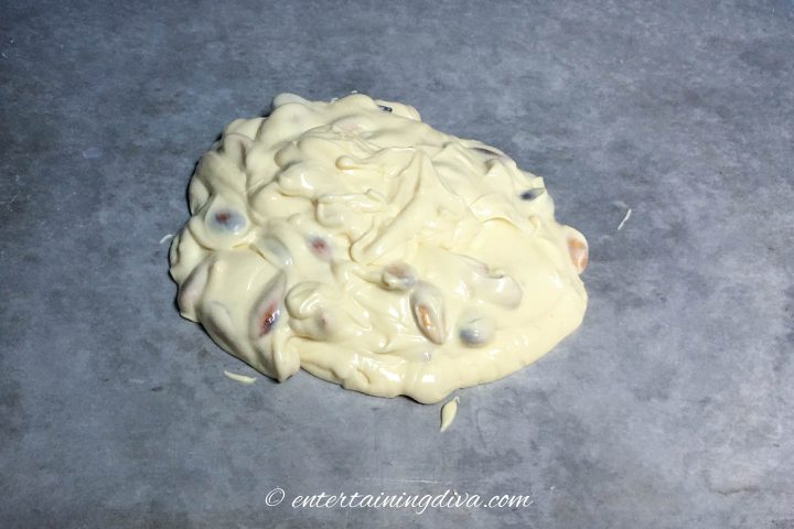 Melted white chocolate and roasted almonds on a cookie sheet