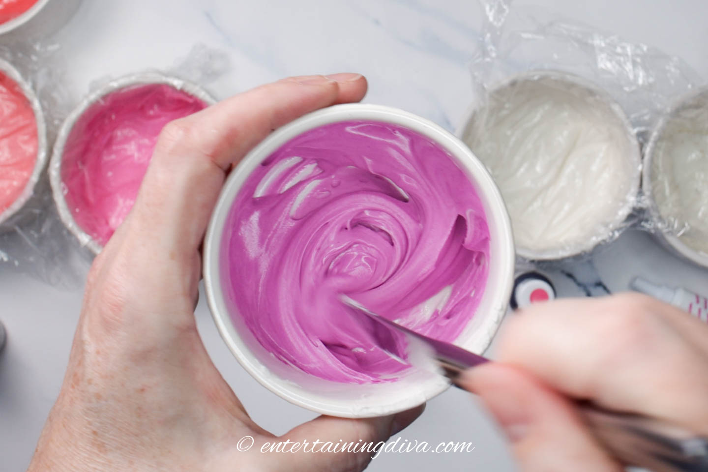 Mauve pink royal icing being mixed in a small bowl