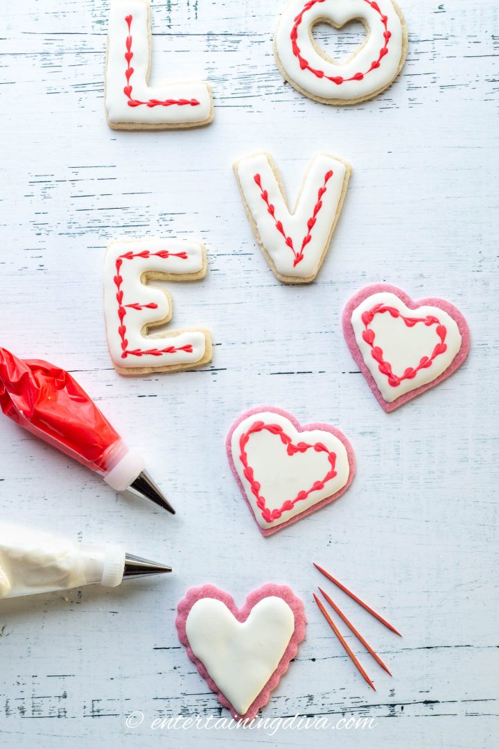 Heart cookies and LOVE cookies decorated with white royal icing and a red joined heart outline