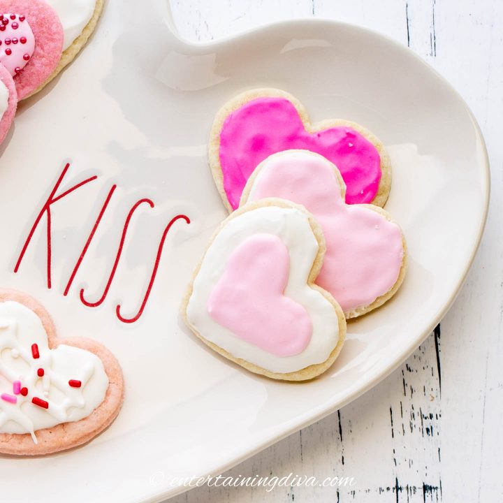 Heart cookies with pink and white royal icing on a heart-shaped plate