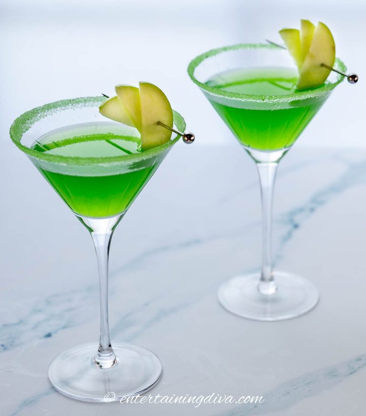 Appletini mocktail garnished with 3 granny smith apple wedges on a cocktail pick