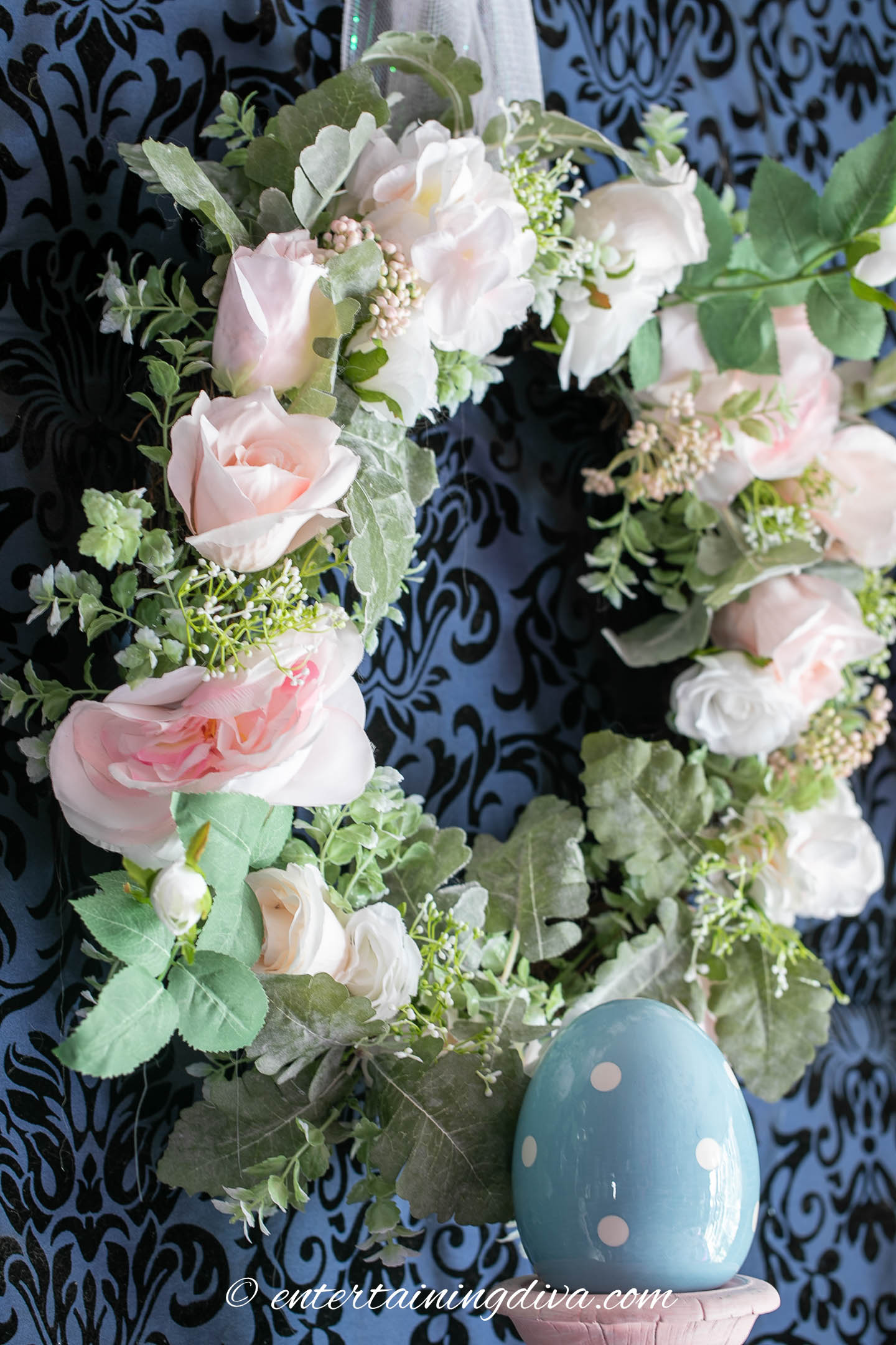 Pink peony and green leaf wreath hanging above a buffet