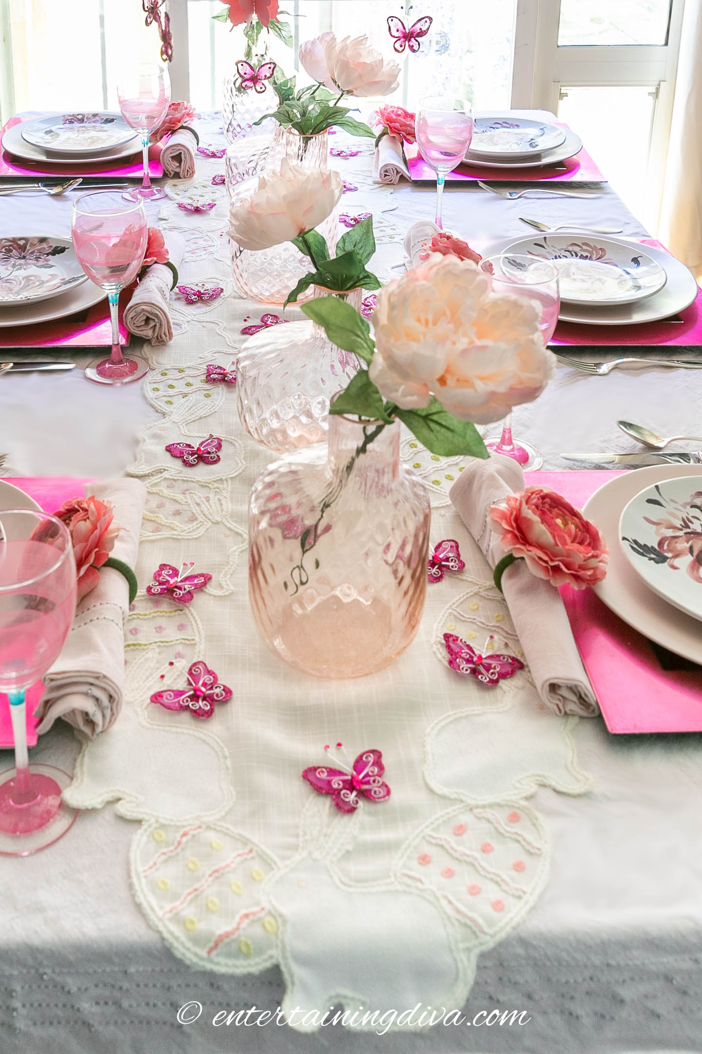 Pink flowers, vases and butterflies use as a centerpiece