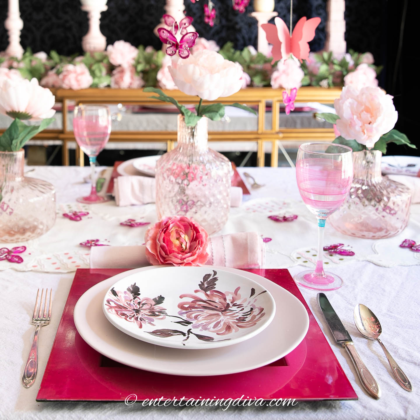 Pink flowers and butterflies place setting with pink striped wine glasses