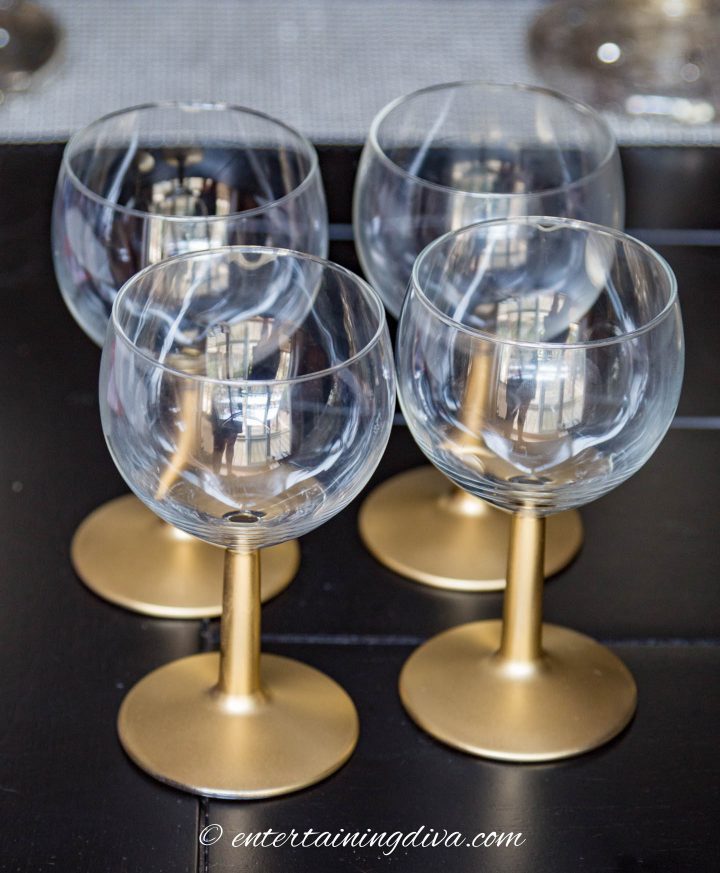 spray painted gold-stemmed wine glasses on a black table