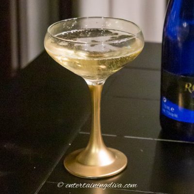 DIY spray painted gold-stemmed coupe glass with champagne in it
