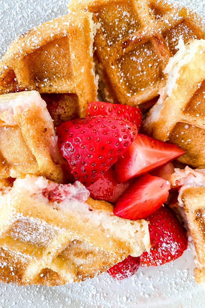 Strawberry cheesecake stuffed waffles on a plate with strawberries