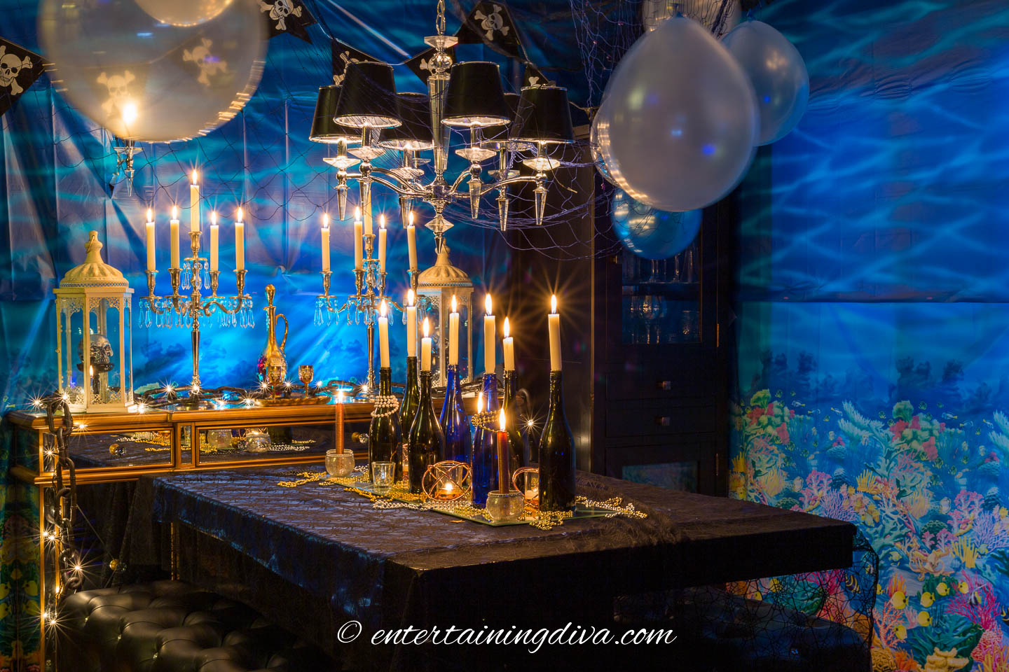 Under the sea party decor with an under the sea scene setter and balloons hung from the ceiling