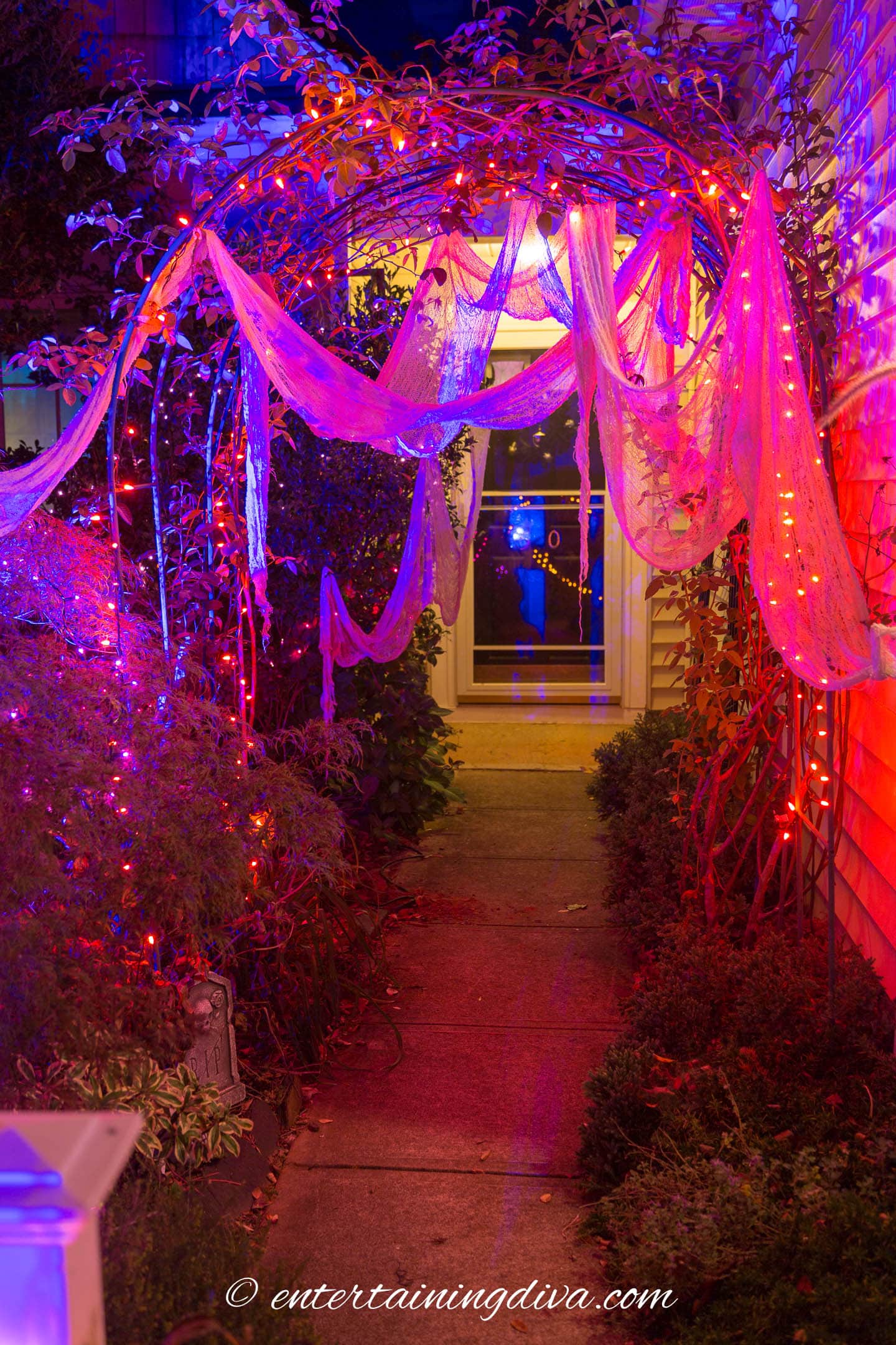 White creepy cloth hung on an arbor with string lights
