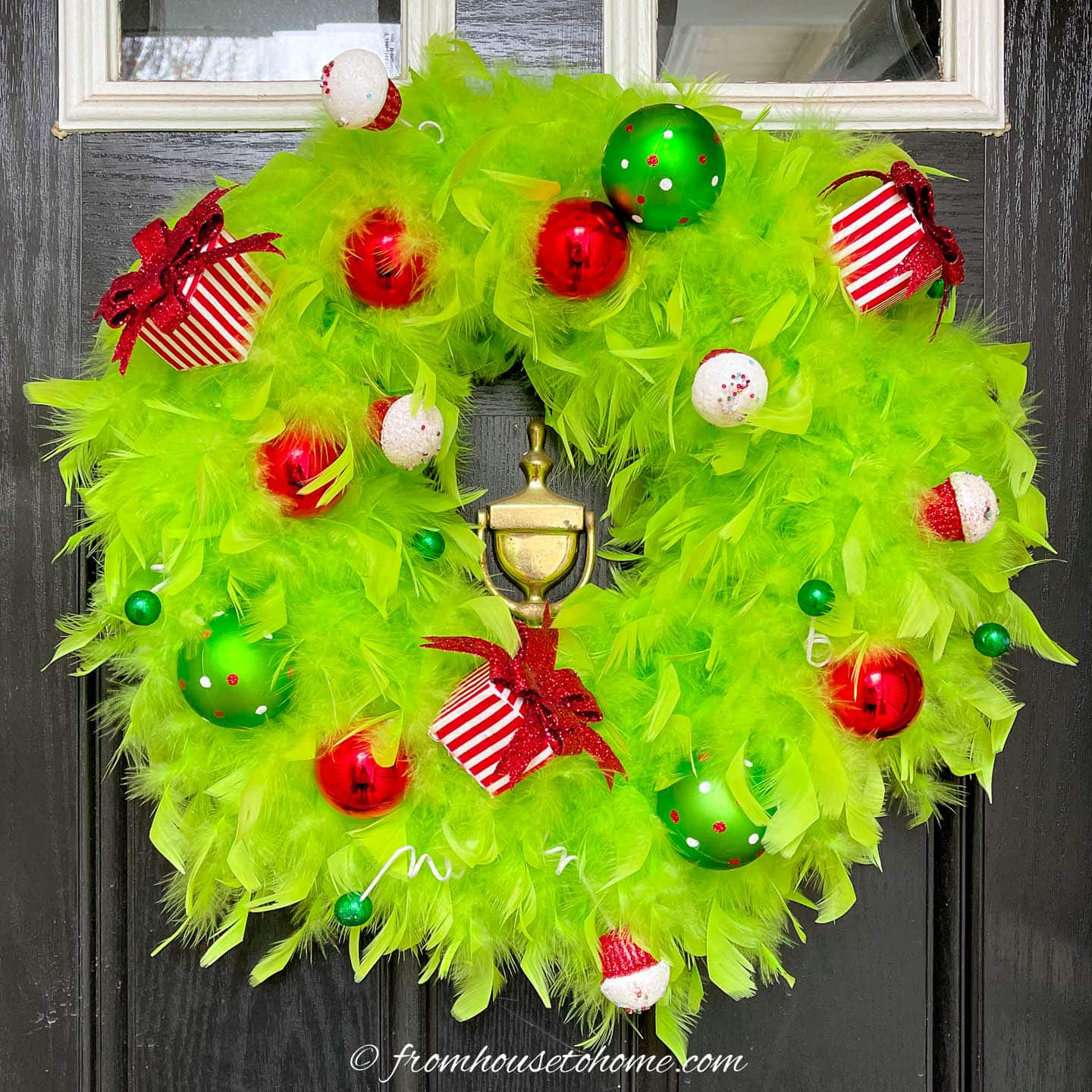 green and red DIY Grinch wreath hanging on a black door