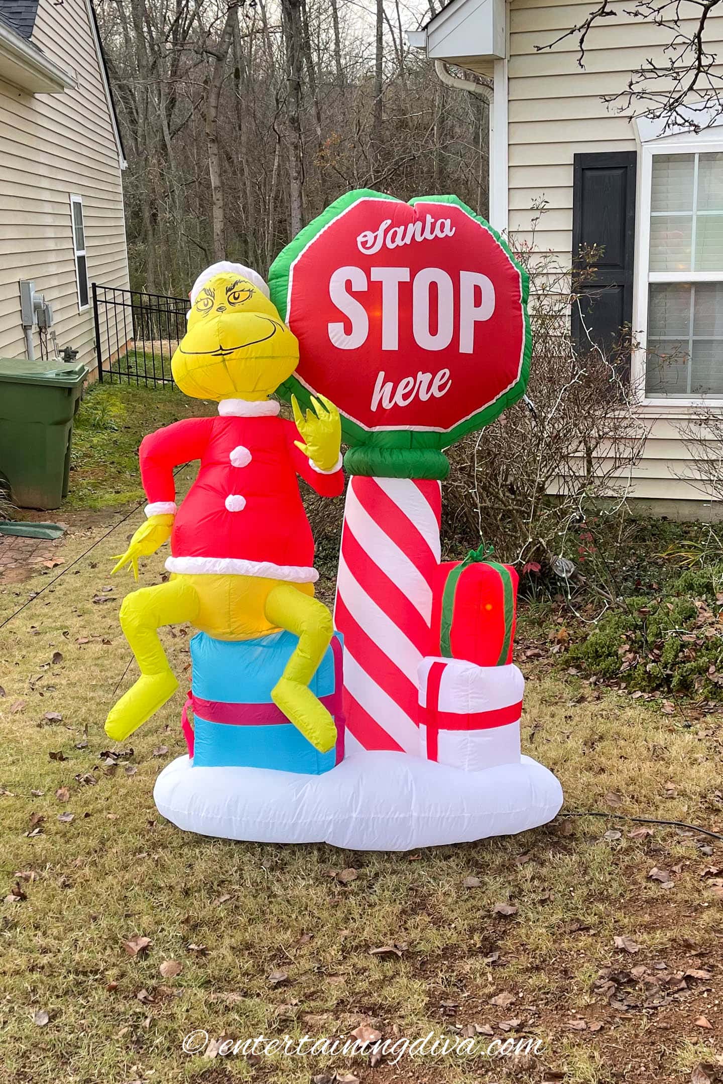 Grinch inflatable with a Santa stop here sign