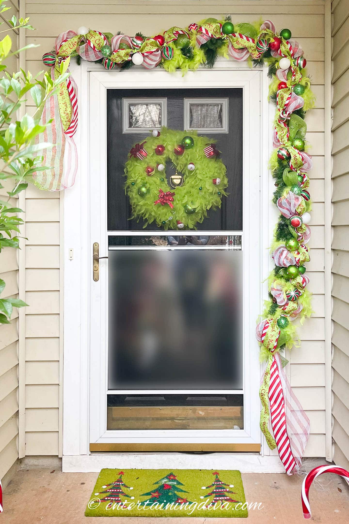 Front door with a Grinch door mat, Grinch garland and Grinch wreath