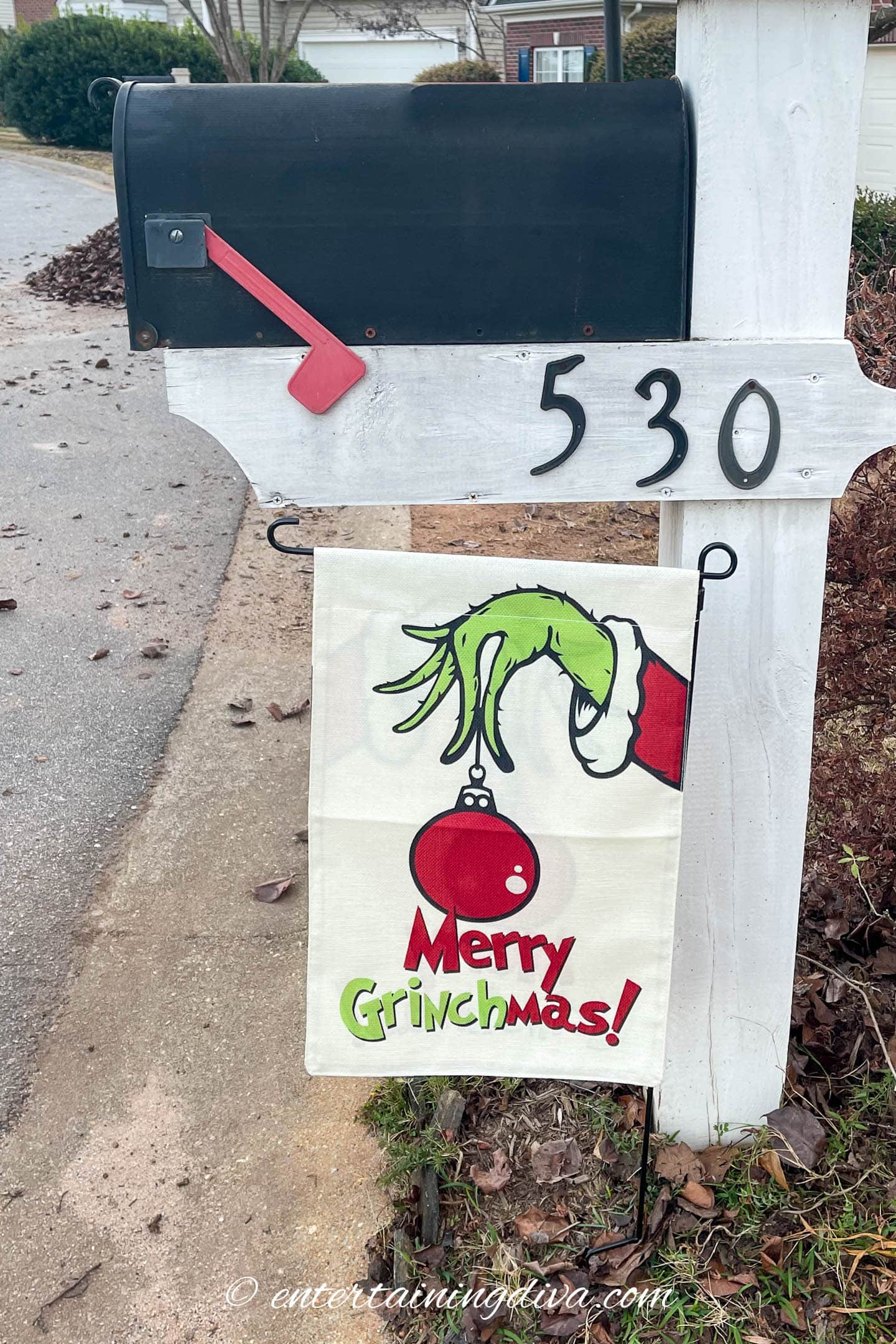Merry Grinchmas garden flag in front of a mailbox