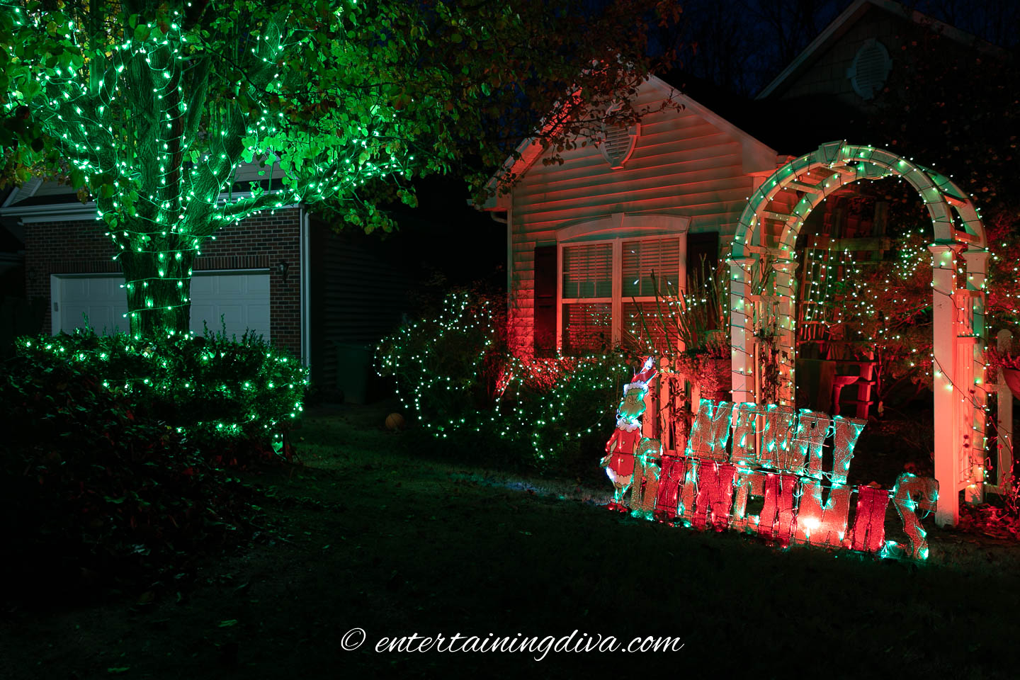 Grinch-inspired outdoor lighting with green lights on the trees and red flood lights