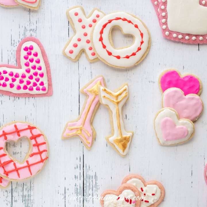 Valentine cookies decorated with white and pink royal icing and gold edible paint